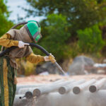 Male,Worker,Sand,Blasting,Process,Cleaning,Pipeline,Surface,On,Steel